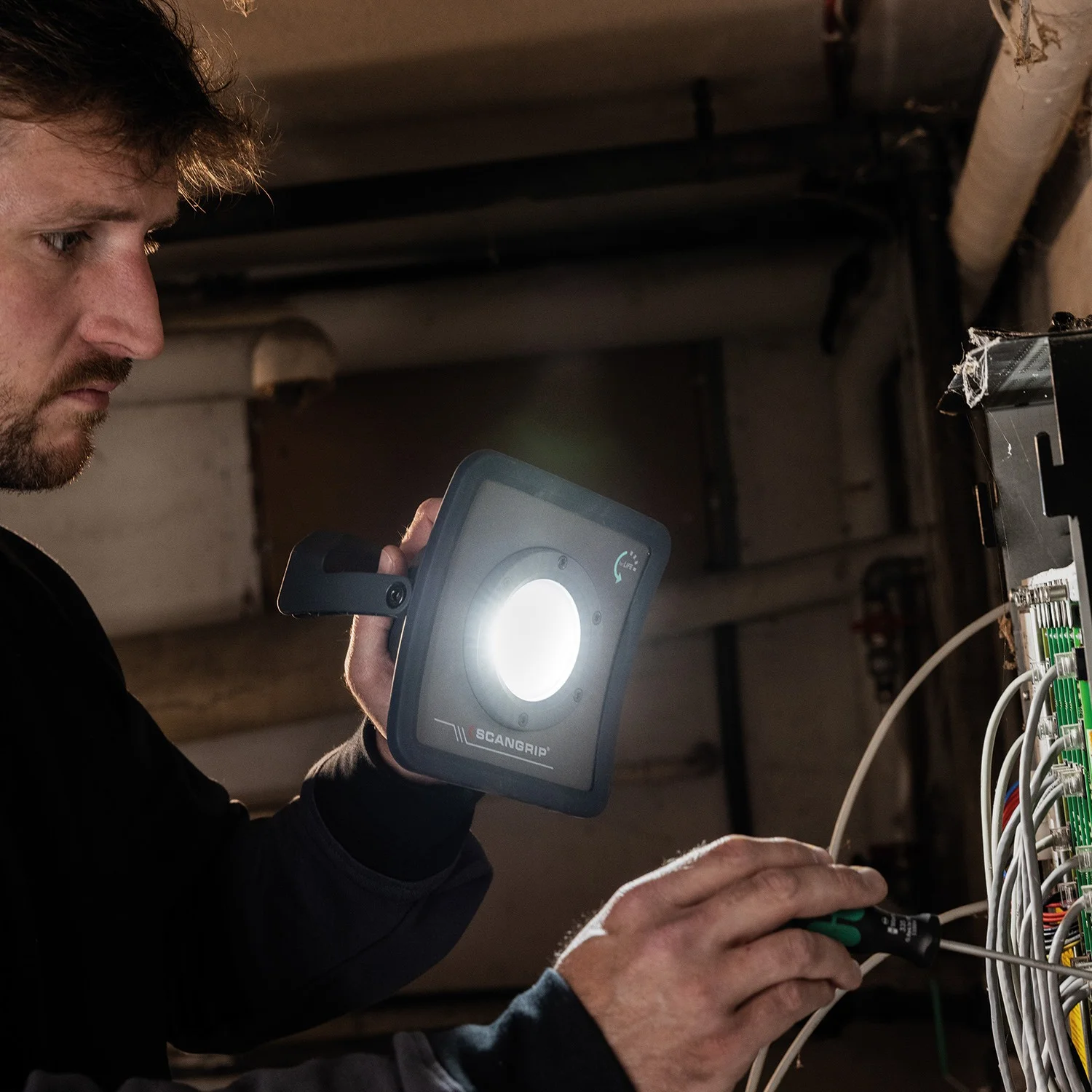 Scangrip LED прожектор NOVA R в ръка при работа по ел. табло